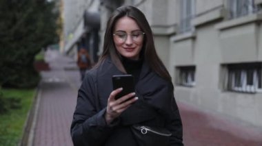Beyaz gömlek giymiş ve modern akıllı telefon, cep telefonu dışında ağır çekim kısa mesaj yazarak profesyonel kadın işveren kullanarak güzel genç kadın