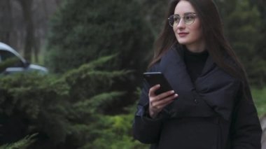 Beyaz gömlek giymiş ve modern akıllı telefon, cep telefonu dışında ağır çekim kısa mesaj yazarak profesyonel kadın işveren kullanarak güzel genç kadın