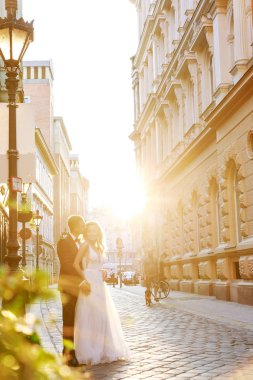 Gelin ve damat kente sokak sarılma. Evlilik çift aşık. Lüks yapay elmas elbise. Sıcak yaz günlerinde.