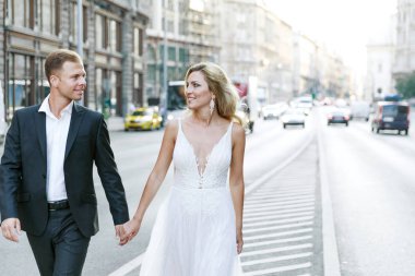 Gelin ve damat kente sokak sarılma. Evlilik çift aşık. Lüks yapay elmas elbise. Sıcak yaz günlerinde.