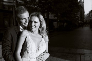 Gelin ve damat kente sokak sarılma. Evlilik çift aşık. Lüks yapay elmas elbise. Sıcak yaz günlerinde.