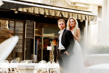 Gelin ve damat kente sokak sarılma. Evlilik çift aşık. Lüks yapay elmas elbise. Sıcak yaz günlerinde.
