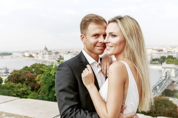 Bride and groom hugging in the old town street. Wedding couple in love. Luxury rhinestone dress. Hot summer days.