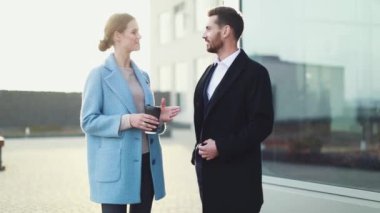 Çekici işkadını kahve gülümseyen ortağı bakmak ve Ofis Binası, yürüme ile. Executive yöneticileri kentsel Caddesi üzerinde çalışacak ön görünümü. Şehir yürüyüş kavramı. Yüksek çözünürlük. İş tarzı. Bahar stili.