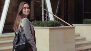 Kendine güvenen genç sıcak, şık bir pembe ceketli sarışın kız Havaalanı terminal tarafından yürür ve cep telefonunu kullanır gülümseyerek mutlu bir şekilde metin mesajları için etrafına bakıyor. Şık kıyafet, modern kadın.