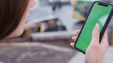 Kız kullanarak telefon yeşil ekran açık havada kentsel çevre iş smartphone krom anahtar parmak modern holding eller akıllı telefon kaydırma fonksiyonları masaj dokunarak görüntülemek
