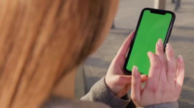 Kız kullanarak telefon yeşil ekran açık havada kentsel çevre iş smartphone krom anahtar parmak modern holding eller akıllı telefon kaydırma fonksiyonları masaj dokunarak görüntülemek