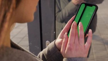 Kız kullanarak telefon yeşil ekran açık havada kentsel çevre iş smartphone krom anahtar parmak modern holding eller akıllı telefon kaydırma fonksiyonları masaj dokunarak görüntülemek