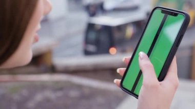 Kız kullanarak telefon yeşil ekran açık havada kentsel çevre iş smartphone krom anahtar parmak modern holding eller akıllı telefon kaydırma fonksiyonları masaj dokunarak görüntülemek