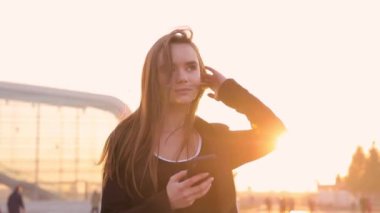 Havaalanı kadınlarda kapısında terminalde bekleyen akıllı telefon. Hava seyahat konsepti ile genç rahat iş kadın konuşmak smartphone, Carry On el Bagaj arabası ile oturuyordu. Güzel genç.