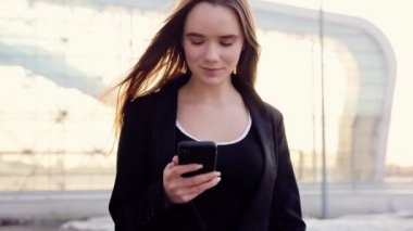 Açık havada, güneş ışığı, yavaş hareket gitmek için smartphone kullanarak ve kahve içme genç profesyonel iş kadını Close-Up