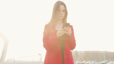 Havaalanı kadınlarda kapısında terminalde bekleyen akıllı telefon. Hava seyahat konsepti ile genç rahat iş kadın konuşmak smartphone, Carry On el Bagaj arabası ile oturuyordu. Güzel genç.