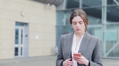 Genç başarılı iş kadını ofis binasının yakınında bir yürüyüş yapıyor. Şık, ciddi görünüyorsun. Klasik takım elbise giyiyor. Kendine güvenen bir yürüyüş. İş yaşam tarzı. Güzel kadın.