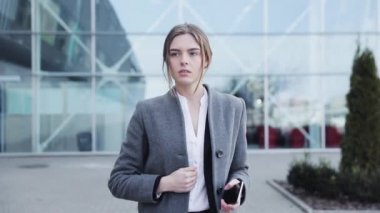 Genç başarılı iş kadını ofis binasının yakınında bir yürüyüş yapıyor. Şık, ciddi görünüyorsun. Klasik takım elbise giyiyor. Kendine güvenen bir yürüyüş. İş yaşam tarzı. Güzel kadın.