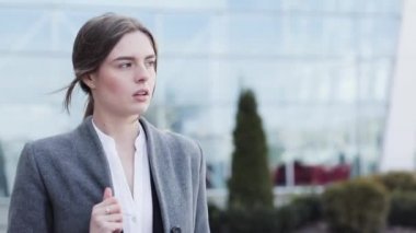 Genç başarılı iş kadını ofis binasının yakınında bir yürüyüş yapıyor. Şık, ciddi görünüyorsun. Klasik takım elbise giyiyor. Kendine güvenen bir yürüyüş. İş yaşam tarzı. Güzel kadın.