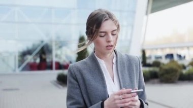 Genç başarılı iş kadını ofis binasının yakınında bir yürüyüş yapıyor. Şık, ciddi görünüyorsun. Klasik takım elbise giyiyor. Kendine güvenen bir yürüyüş. İş yaşam tarzı. Güzel kadın.
