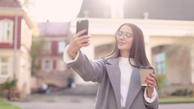 Genç kadın manifatura ya da telefon kullanarak ve sokakta kahve içme