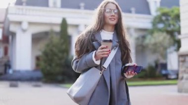 Genç kadın manifatura ya da telefon kullanarak ve sokakta kahve içme