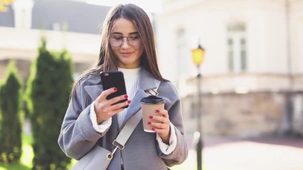 Mujer Joven Mensajes Texto Uso Teléfonos Inteligentes Beber Café Calle — Vídeo de stock
