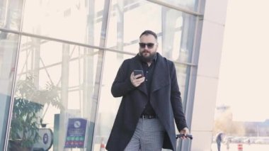 Telefonun ses tanıma kullanarak bir adamın portresi ve tatil turist konuşma kişisel asistan doğal dil kullanıcı arayüzü Havaalanı Terminali yakınında cep telefonu bakıyor.