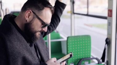 Toplu taşıma üzerinde yakışıklı adam ayakta görünümü yakın. Kalabalık tramvay iç. Cep telefonu adam türleri. Casual giyim.