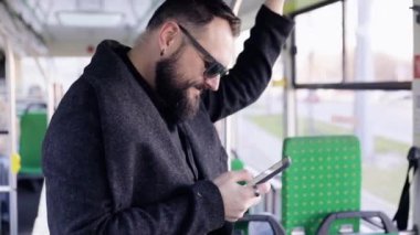 Toplu taşıma üzerinde yakışıklı adam ayakta görünümü yakın. Kalabalık tramvay iç. Cep telefonu adam türleri. Casual giyim.