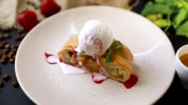 Siyah arka plan üzerinde, tabakta dondurma, taze çilek ve nane yaprakları ile lezzetli ev yapımı strudel . Yavaş mo