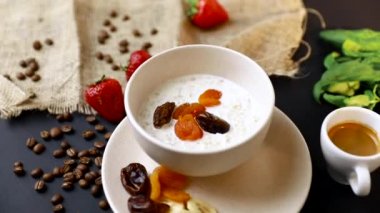 Lezzetli kahvaltı. Siyah masa üzerinde yulaf, fındık ve kurutulmuş meyve ile müsli bir kase üst görünümü. Yavaş mo