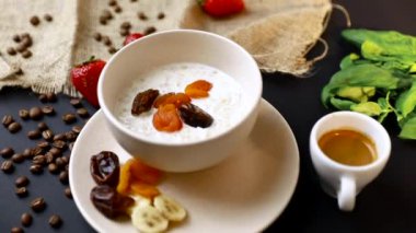 Lezzetli kahvaltı. Siyah masa üzerinde yulaf, fındık ve kurutulmuş meyve ile müsli bir kase üst görünümü. Yavaş mo