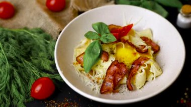 Pastırma makarna yumurta - Çiğ yumurta üst görünümü ile bir tabakta İtalyan Carbonara. Siyah arka plan . Yavaş mo