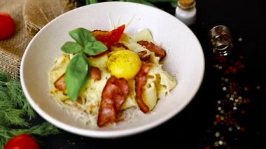 Pastırma makarna yumurta - Çiğ yumurta üst görünümü ile bir tabakta İtalyan Carbonara. Siyah arka plan . Yavaş mo