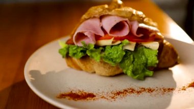 Jambon ve peynirile kahvaltılık kruvasan sandviç. Üst te. sebze ile siyah arka plan. Yavaş mo