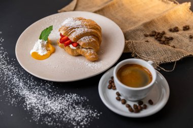 Taze kruvasan, bir fincan kahve ve siyah arka planda çilek reçeli ile kahvaltı, Slow-mo