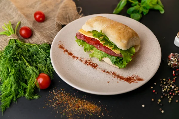 Tasty breakfast. sandwich with smoked ham, cheese, tomato and lettuce served on a white plate.Black background . Slow-m
