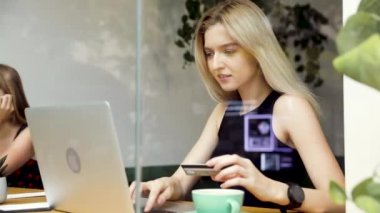 Çekici genç kadın kafede dizüstü bilgisayara bir kredi kartı numarası girerken online alışveriş. Içinde