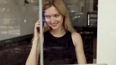 Dizüstü bilgisayar kullanarak masada oturan, çağrıya cevap veren, telefonda konuşan, cep telefonuyla konuşan genç, kafede bilgisayarla çalışırken cep telefonundan keyifli sohbet ler veren genç,