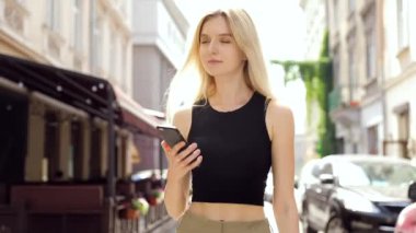 beyaz gömlek giyen ve şehirde mola yürürken modern akıllı telefon kullanarak eautiful genç iş kadını, profesyonel kadın işveren dışında cep telefonu metin mesajı yazarak, yavaş hareket