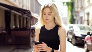 Mutlu Gülümseyen Çekici Kadın Sokakta Yürürken. İlgiyle Akıllı Telefonunda Yazarak. Akşam Yürüyüşü'nün tadını çıkarıyorum. Arka Planda Kalabalık Şehir.