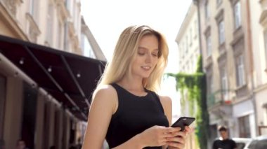Siyah gömlek giyen ve modern akıllı telefon kullanarak güzel genç kadın, profesyonel kadın işveren dışında cep telefonu metin mesajı yazarak, yavaş hareket
