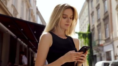 Siyah gömlek giyen ve modern akıllı telefon kullanarak güzel genç kadın, profesyonel kadın işveren dışında cep telefonu metin mesajı yazarak, yavaş hareket