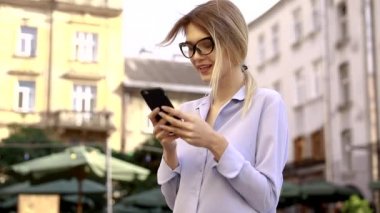 Mavi gömlek giyen ve modern akıllı telefon kullanarak güzel genç kadın, profesyonel kadın işveren dışında cep telefonu metin mesajı yazarak, yavaş hareket