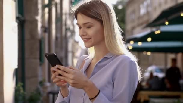 美丽的年轻女子穿着蓝色衬衫 使用现代智能手机 专业女雇主在手机外输入短信 慢动作 — 图库视频影像