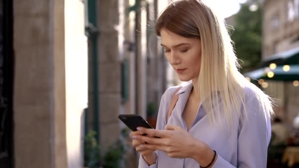 美丽的年轻女子穿着蓝色衬衫 使用现代智能手机 专业女雇主在手机外输入短信 慢动作 — 图库视频影像