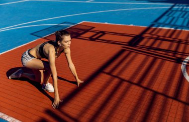 Bir stadyumda hızlı başlangıç konumuna sarışın sportif kadın Runner.