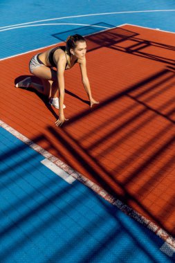 Bir stadyumda hızlı başlangıç konumuna sarışın sportif kadın Runner.