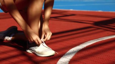 Genç kadın ayakkabılarına bağlanıyor, böylece koşmaya başlayabilir.