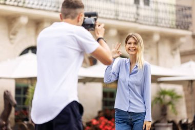 Turist çift. Kamera çekim kadının sokakta olan adam. Gülümseyen genç Çift seyahat ve fotoğrafları açık havada yapma şık giysiler içinde aşık. İnsanlar seyahat hafta sonu. Yüksek çözünürlük.