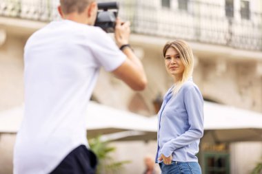 Turist çift. Kamera çekim kadının sokakta olan adam. Gülümseyen genç Çift seyahat ve fotoğrafları açık havada yapma şık giysiler içinde aşık. İnsanlar seyahat hafta sonu. Yüksek çözünürlük.
