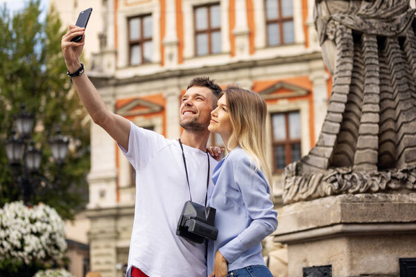 Travel selfie couple taking photo with phone at historical  city. Europe summer vacation young people smiling. Backpacking road trip. High Resolution. 