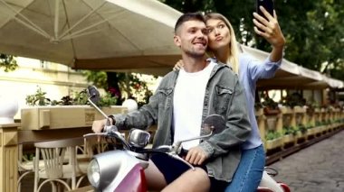 Scooter'daki mutlu çift, dışarıda akıllı telefonda selfie fotoğrafı çekiyor. İnsanlar hafta sonu seyahat. Yüksek Çözünürlük.